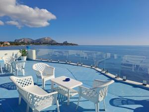 a patio with chairs and a table and the ocean at Blue Life, sea-luxury rooms on the beach between Palermo and Cefalu' in Casteldaccia