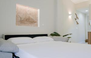 um quarto com uma cama branca e uma pintura na parede em Casa Colgante con vistas panorámicas junto al mar. em Villajoyosa