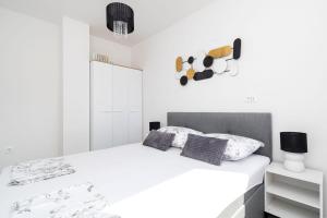 a white bedroom with a bed with white walls at Apartments Grubišić - Šibenik - parking included in Šibenik