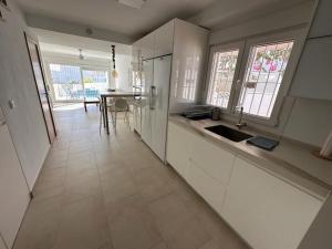 una cucina con armadi bianchi, lavandino e tavolo di Idílica casa en Atlanterra a Zahara de los Atunes