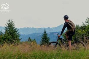 a person standing next to a bike in a field at Armadillo Houses in Kopaonik