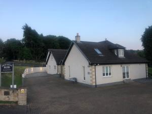 ein weißes Haus mit einem schwarzen Dach und einer Auffahrt in der Unterkunft Druid Apartment in Inverness