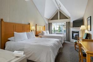 Habitación de hotel con 2 camas y chimenea en Pinnacle Hotel Whistler en Whistler