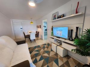 sala de estar con sofá blanco y TV de pantalla plana en PACIFIC - PRAIA DO FORTE, en Cabo Frío