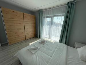 een slaapkamer met een groot wit bed en een raam bij Noah Apartment Self Check-in Otopeni in Otopeni