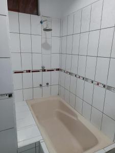 a white tiled bathroom with a large bath tub at Majestic Mical in Yurimaguas