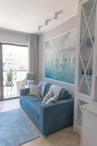 een woonkamer met een blauwe bank en een schilderij van zeilboten bij SHELLTER Apartament Blue Dune-Rogowo in Rogowo