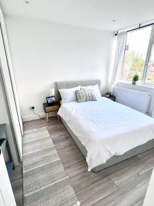 een witte slaapkamer met een bed en een raam bij Beautiful 5-bedroom private house in quiet London street 2 minutes from station in Londen