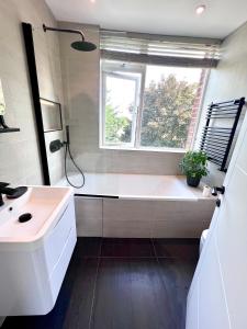 een badkamer met een bad, een wastafel en een raam bij Beautiful 5-bedroom private house in quiet London street 2 minutes from station in Londen