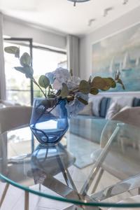 uma mesa de vidro com um vaso azul com flores em SHELLTER Apartament Blue Dune-Rogowo em Rogowo