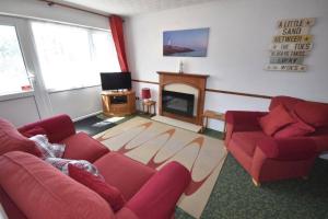 a living room with two red couches and a fireplace at Lighthouse View in Winterton-on-Sea