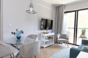 a white living room with a glass table and chairs at SHELLTER Apartament Blue Dune-Rogowo in Rogowo