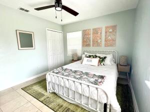 Palm Paradise in downtown Cocoa Beach في كوكاو بيتش: غرفة نوم بسرير أبيض ومروحة سقف