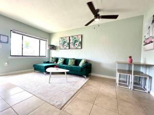 a living room with a green couch and a ceiling fan at Palm Paradise in downtown Cocoa Beach in Cocoa Beach