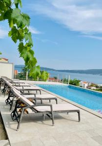 una fila de bancos sentados junto a una piscina en Villa Mediterano, en Herceg-Novi