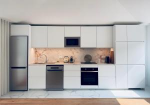 a white kitchen with white cabinets and appliances at Vibrant Porto Apartments-Campo 24 Agosto in Porto