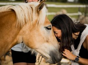 Una mujer está abrazando a un caballo marrón en Ranch Terra en Irinovac