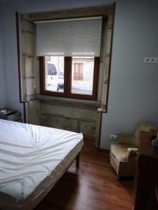 1 dormitorio con cama, ventana y silla en Casa vacacional, en Porto do Son