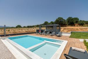 a swimming pool on a patio with chairs around it at Villas 107 - Homeleader in Maleme