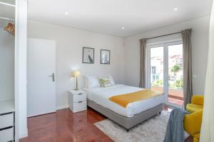 a white bedroom with a bed and a window at Cascais Alvide Guesthouse in Cascais