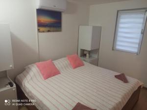 1 dormitorio con 1 cama con 2 almohadas rosas en Sunce apartman Bratkovice 1-8c, en Drače