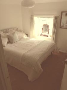 a bedroom with a white bed with a chair and a window at Number Five in Abbotsbury
