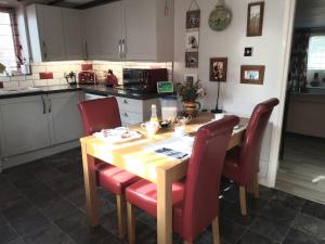 cocina con mesa de madera y sillas rojas en Number Five, en Abbotsbury