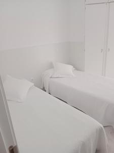três camas num quarto com paredes brancas em La casa blanca em La Pineda