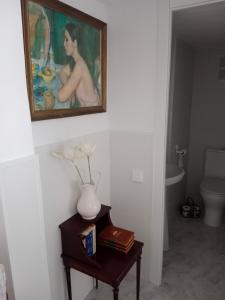 a bathroom with a vase on a table with a painting at La casa blanca in La Pineda