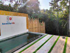 una piscina de agua junto a una valla de madera en Baruna Sari Villa en Ubud
