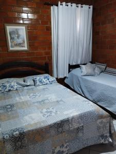 two beds in a room with a brick wall at Chalé aconchegante na Serra Pernambucana - Em condomínio - Gravatá in Gravatá +54 photos