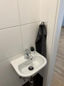 a white sink in a white tiled bathroom at Paky Appartements 00313 in Bruck an der Leitha