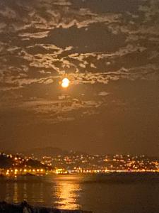 Una luna llena elevándose sobre una ciudad por la noche en Fenix loft spa, en Ardeşen