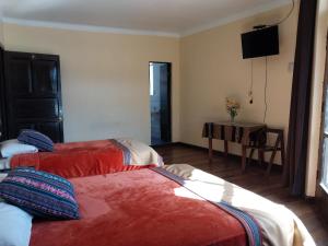2 camas en una habitación con TV en la pared en Hospedaje Balcón Cusqueño, en Cusco