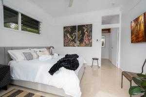 a white bedroom with a white bed and some paintings at URALLA STUDIO - South Coast - Private Guest Suite in Bomaderry