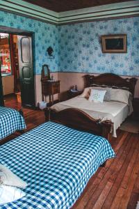 a bedroom with two beds and blue wallpaper at Hotel Finca el Recreo in Guasca