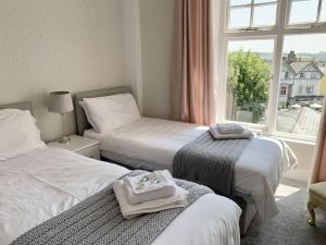 two beds in a room with a window at Seaclyffe Hotel Ltd in Llandudno