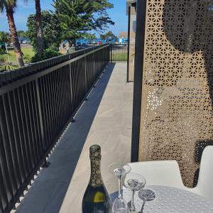 a bottle of wine sitting on a table with wine glasses at Orewa Beachcomber in Orewa