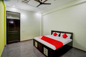 Schlafzimmer mit einem Bett mit roten und weißen Kissen in der Unterkunft OYO Flagship J M K Love Residency in Noida