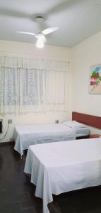 a bedroom with two beds and a ceiling fan at Falcon Hotel in Bauru