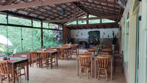 a restaurant with wooden tables and chairs and windows at Hotel Solar Fazenda Do Cedro in Itaipava