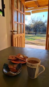 una taza de café sentada en una mesa con un plato de comida en Saucearriba, Saucelinda. en Villa Dolores