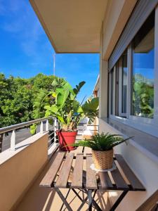 a wooden table on a balcony with two plants at Villa Prana Guesthouse, Yoga & Ayurveda in Portimão