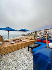 a patio with blue couches and umbrellas on the beach at Single fin beach house in Taghazout