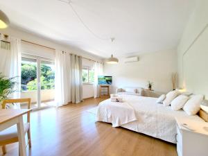 a white bedroom with a large bed with white pillows at Villa Prana Guesthouse, Yoga & Ayurveda in Portimão