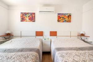 2 camas en una habitación blanca con pinturas en la pared en El Remanso, en Sevilla