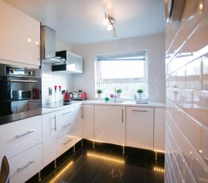 a kitchen with white cabinets and a black floor at So-Cute Cityside in Belfast