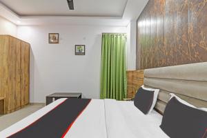 a bedroom with a bed and a green curtain at Collection O The Crestelia in Lucknow