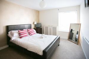 Un dormitorio con una cama con almohadas rojas y blancas y un espejo. en So-Cute Cityside en Belfast