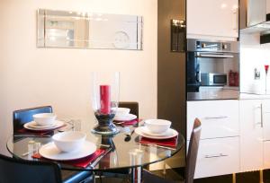 een eetkamer met een glazen tafel met borden en kommen bij So-Cute Cityside in Belfast